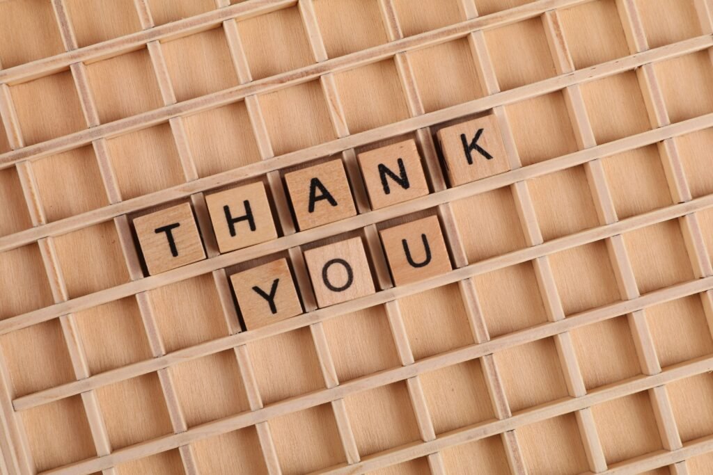 Wooden letter tiles spelling 'thank you' on a grid background, perfect for gratitude themes.